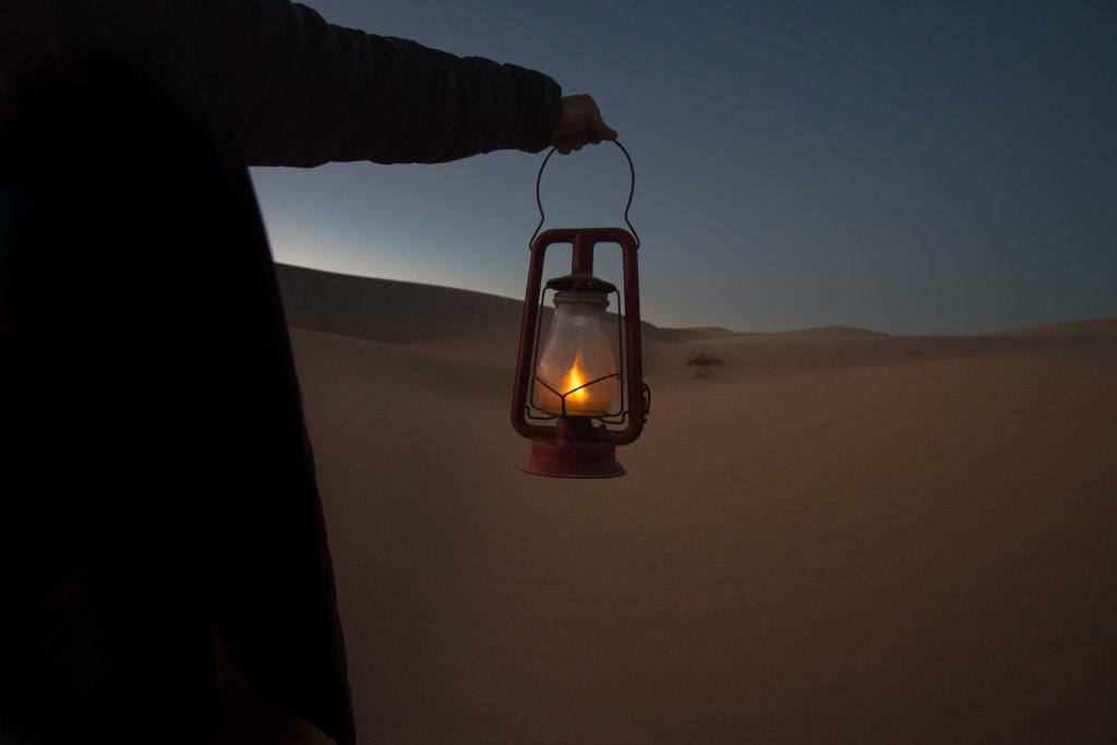 arm outstretched with lantern at night