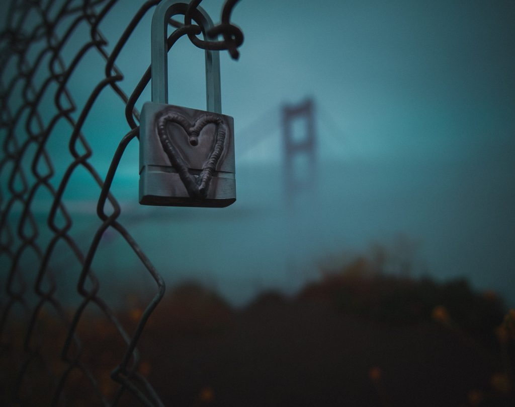 padlock with heart against misty blue background with Golden Gate Bridge tower in distance