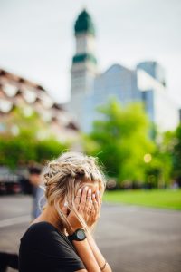 woman weeping into her hands on park bench