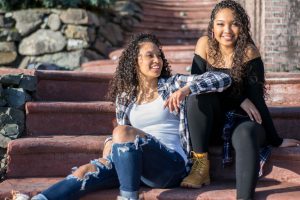 Two young women sitting on stoop together, enjoying their companionship, having nothing to hide from one another.